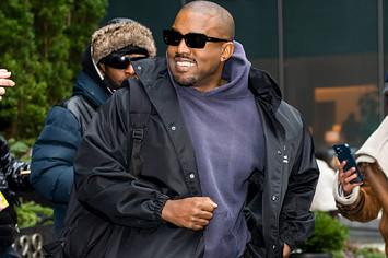 Ye is pictured smiling in front of photographers