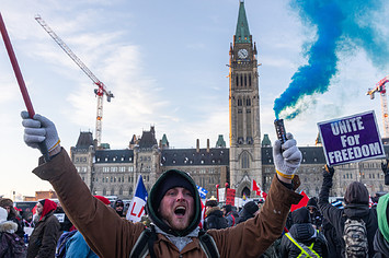 Protestors on parliament hill with signs and smoke flares