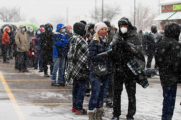 People wearing face masks line up to pick up free COVID-19 antigen rapid test kits in Mississauga