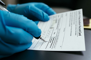 A doctor filling out a COVID-19 vaccination card