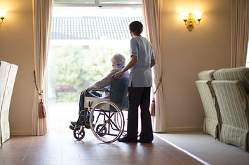 Nurse pushing patient in wheelchair at nursing home
