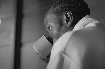 A man is seen sipping coffee in loungewear.