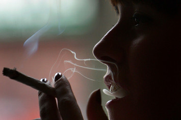 A woman smokes a cigarette of marijuana in an Amsterdam cafe.