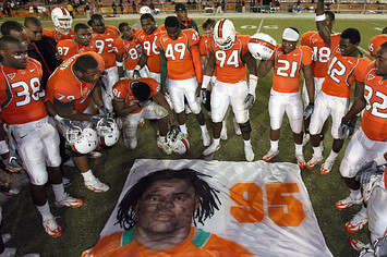 Teammates of Bryan Pata #95 of the University of Miami Hurricanes say a prayer over a mural that was placed at mid-field.