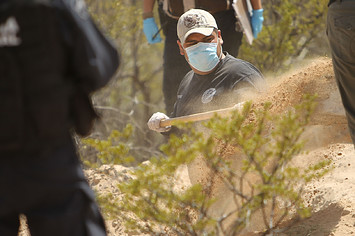 Mexican police and forensic workers dig at a site believed to hold the remains of numerous victims of recent drug violence.