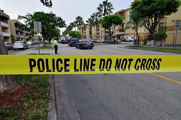 Police tape blocks the street to an apartment building