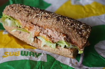 A "Tuna Sandwich" from the fast food chain "Subway" lies on a table.