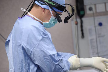 A surgeon puts on gloves before an open-heart surgery