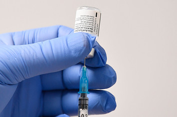 A member of staff uses a needle and a phial of Pfizer-BioNTech Covid-19 vaccine to prepare a dose.