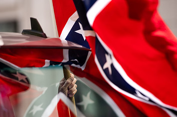 A man holds a Confederate flag while participating in a protest.