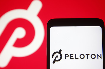 In this photo illustration a Peloton logo is seen on a smartphone and a pc screen.