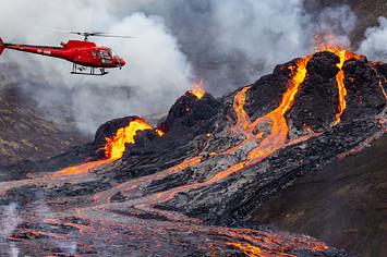 A helicopter flies close to a volcanic eruption