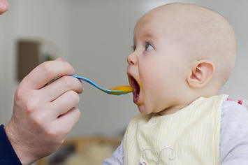 Father spoon feeding baby daughter.