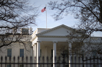 Morning sunlight strikes the flag flying above the White House.