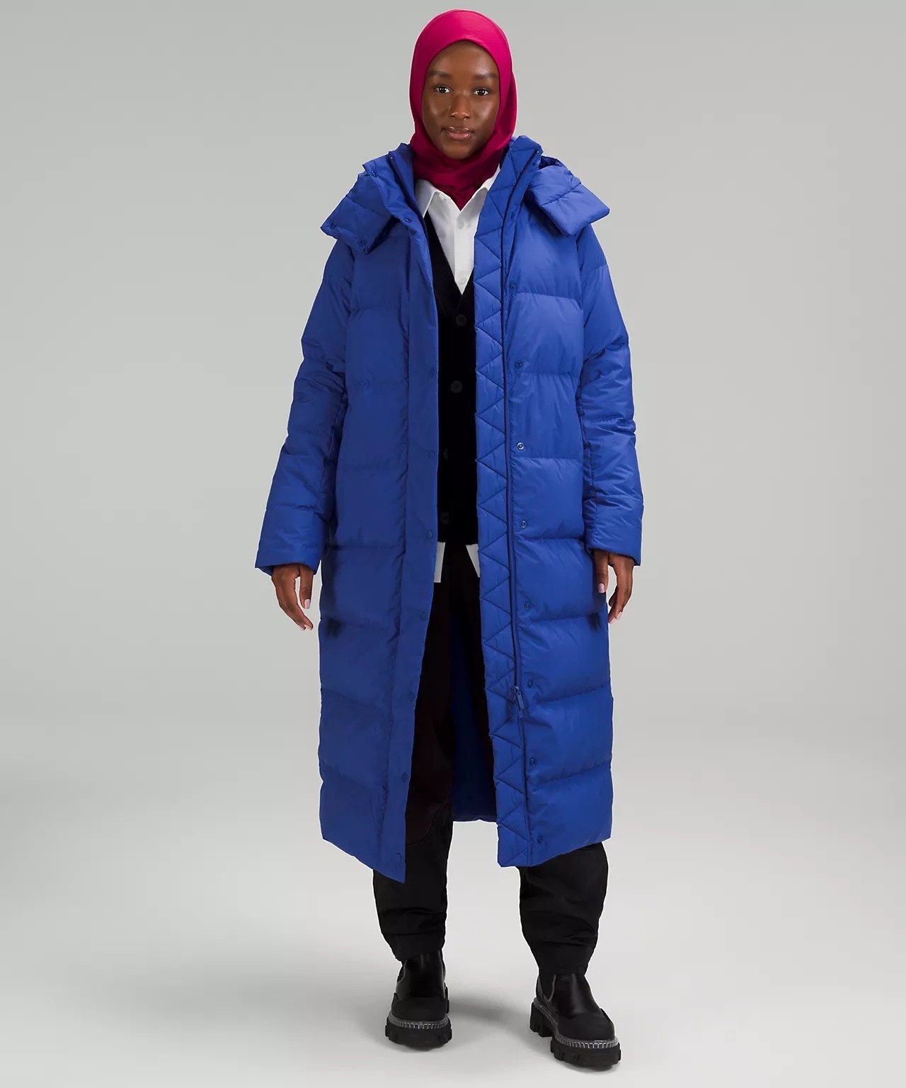 Model wearing blue puffer coat over black and white outfit
