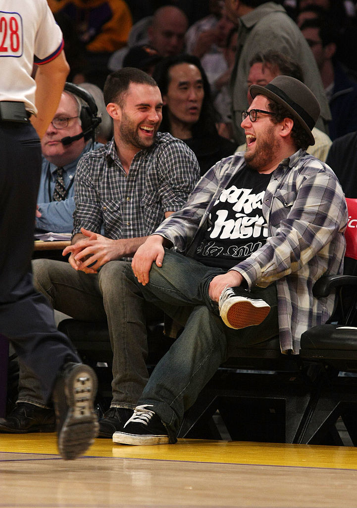 Adam and Jonah sitting and laughing together in the audience of a basketball game