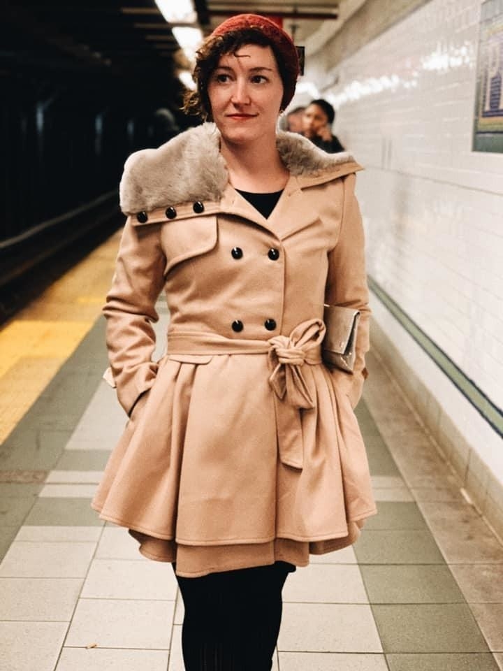 A reviewer wearing an brown coat with black pants