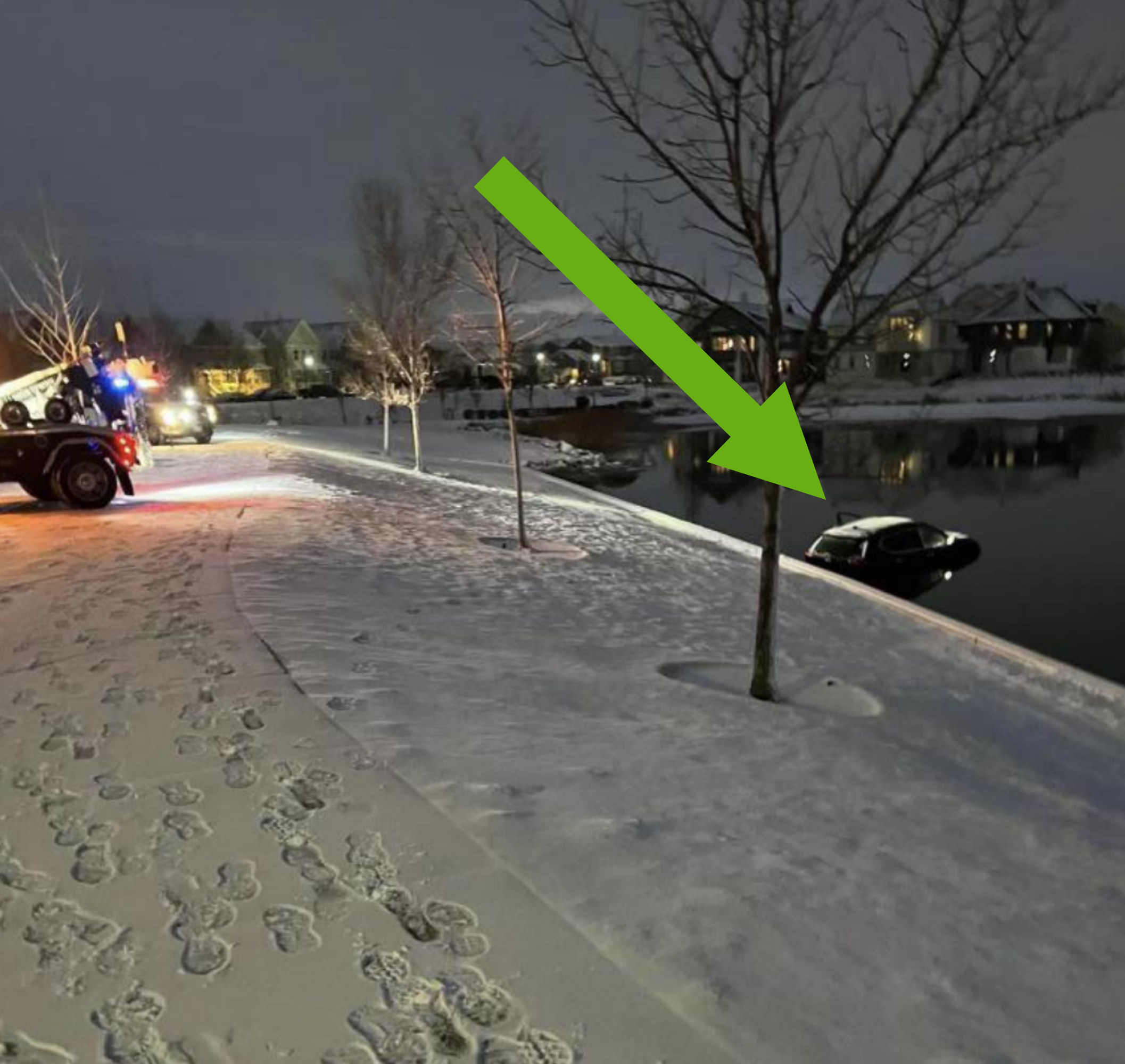 Arrow pointing to a car in the water next to a snowy street