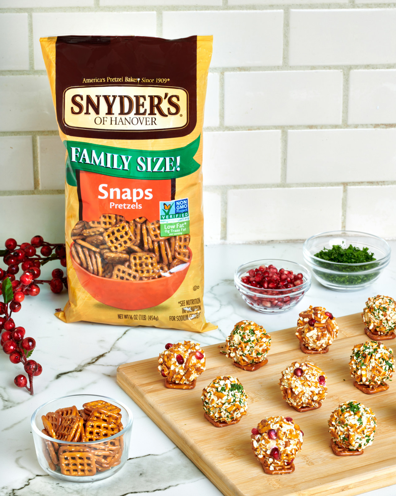 Garlic cheese balls sit on cutting board next to bag of pretzel snaps