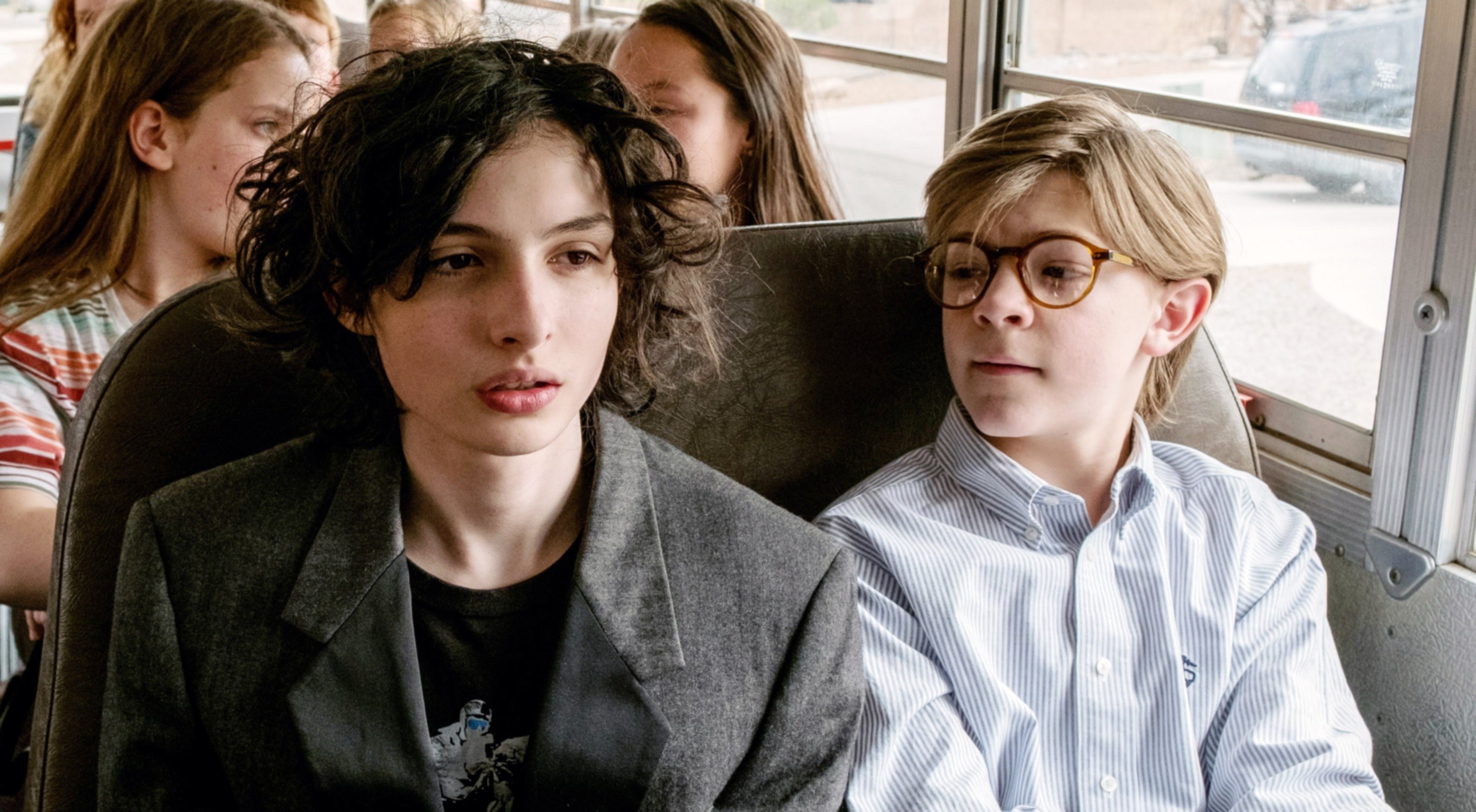 two boys sitting on a school bus together