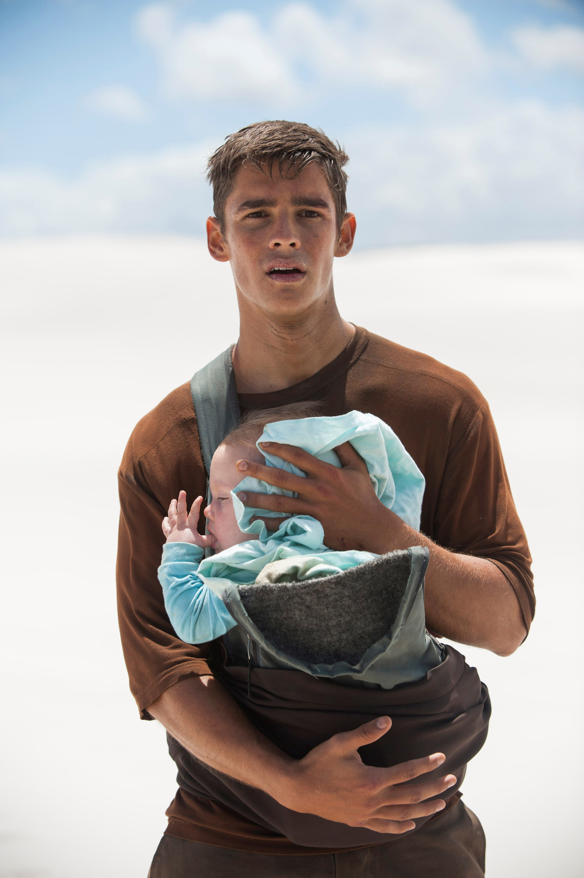 a young man carrying a baby and looking distressed