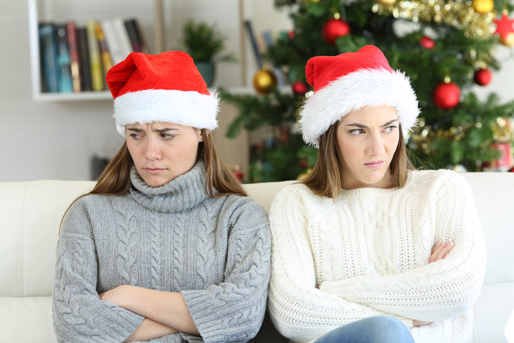 Two women in Santa hats avoiding talking to each other