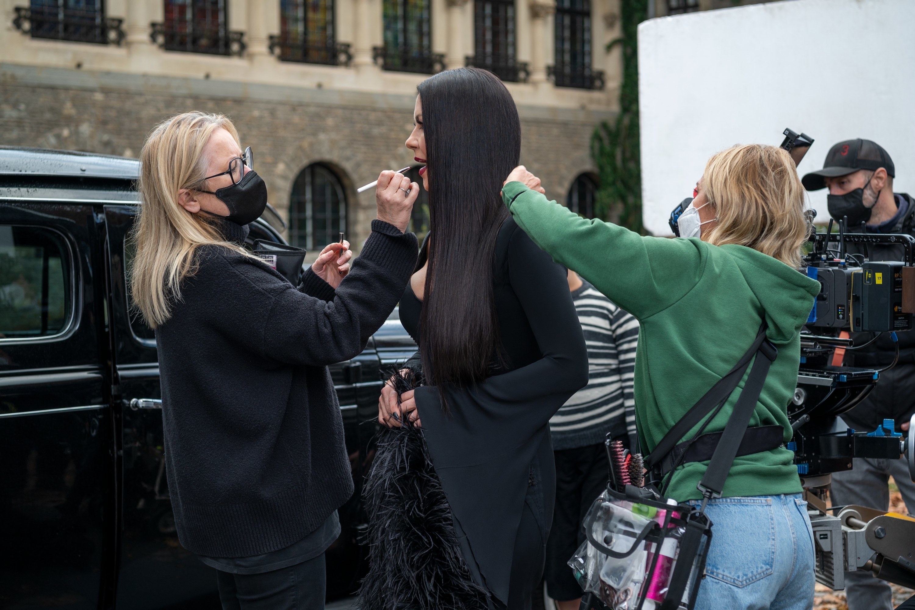 a team touching up morticia&#x27;s makeup on set