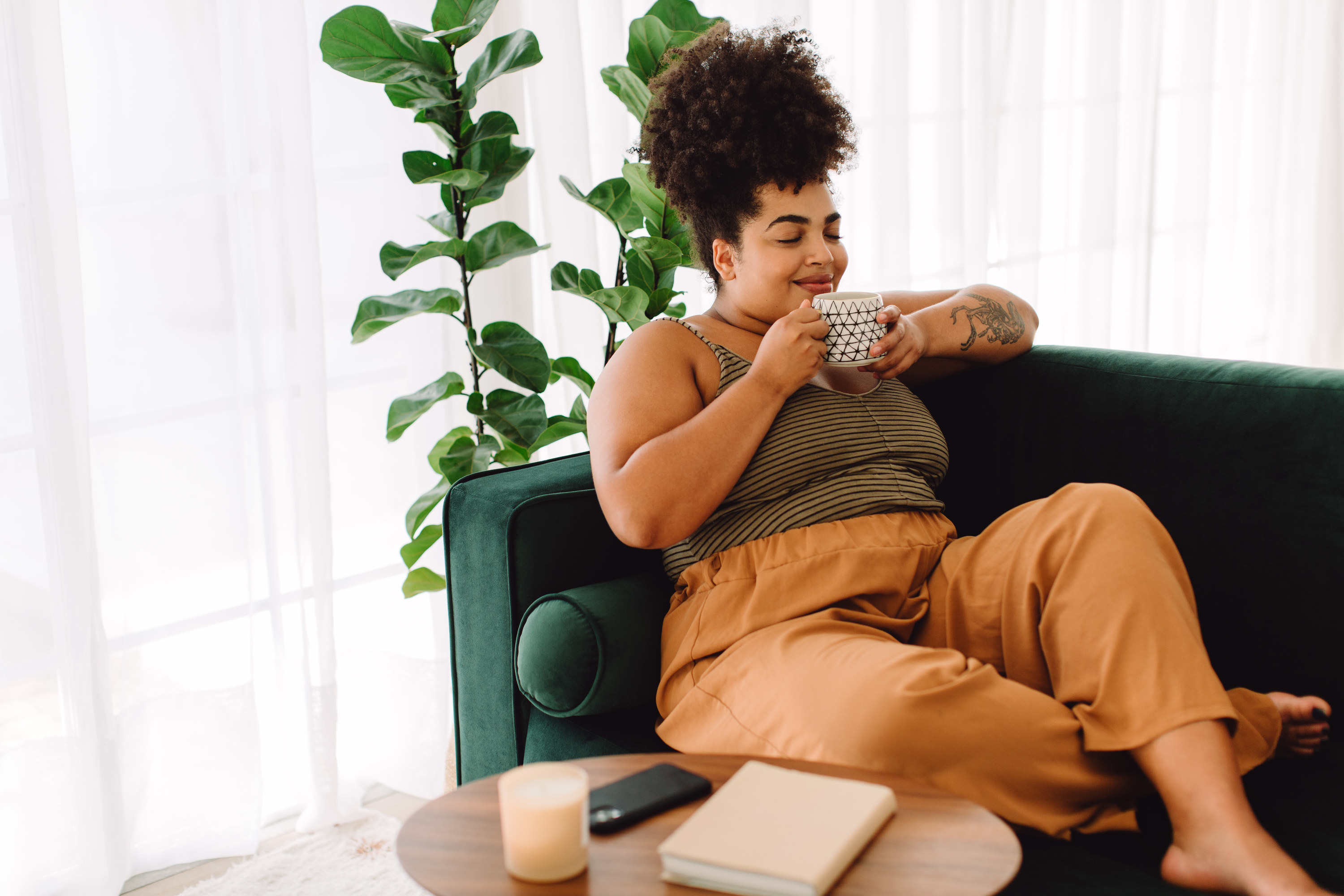 a woman sitting on the couch and drinking coffee