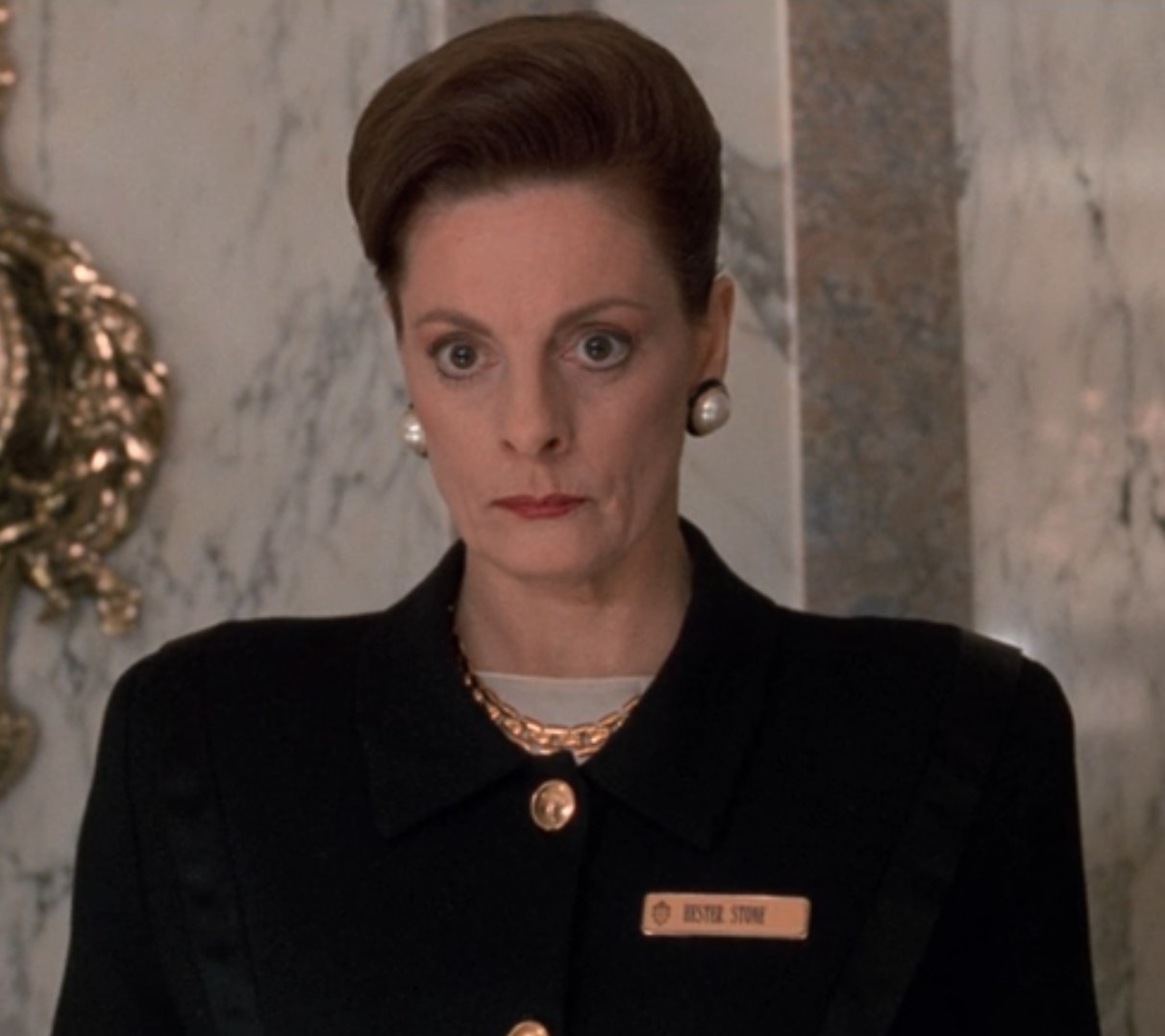 Dana Ivey as Hester greets Kevin at the Plaza Hotel front desk