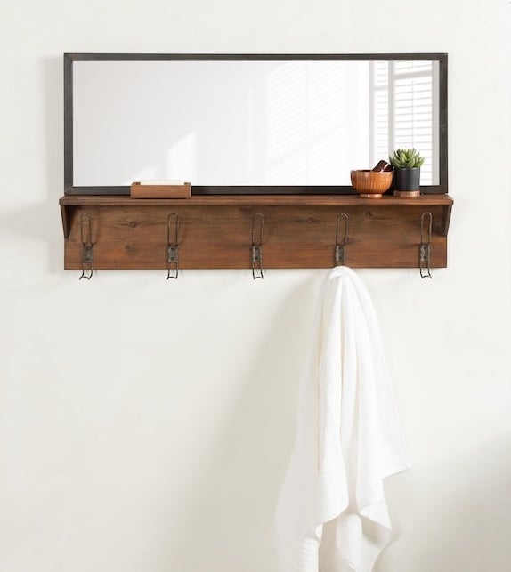 the wall mirror with a plant on the shelf and towel hanging on the hook