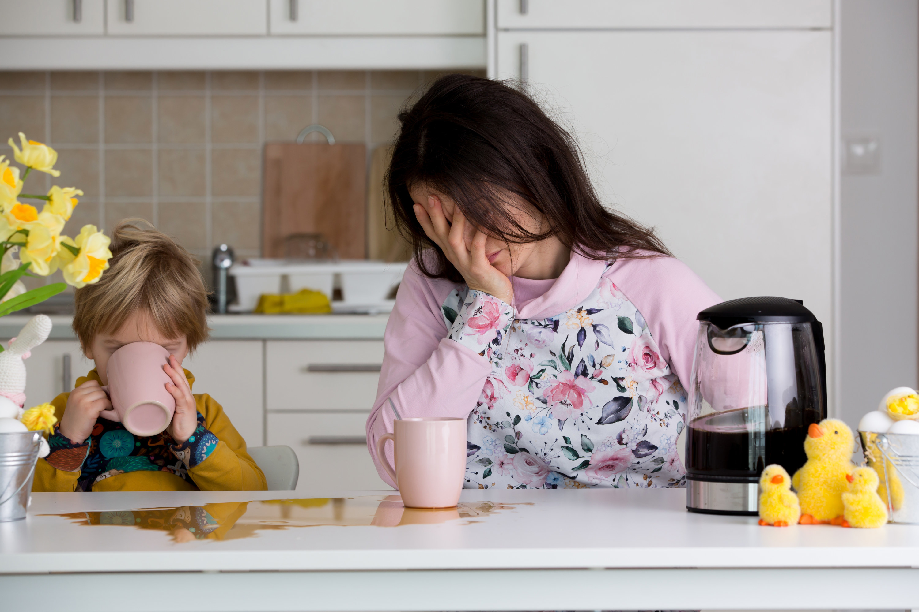 exhausted mom drinking coffee with toddler