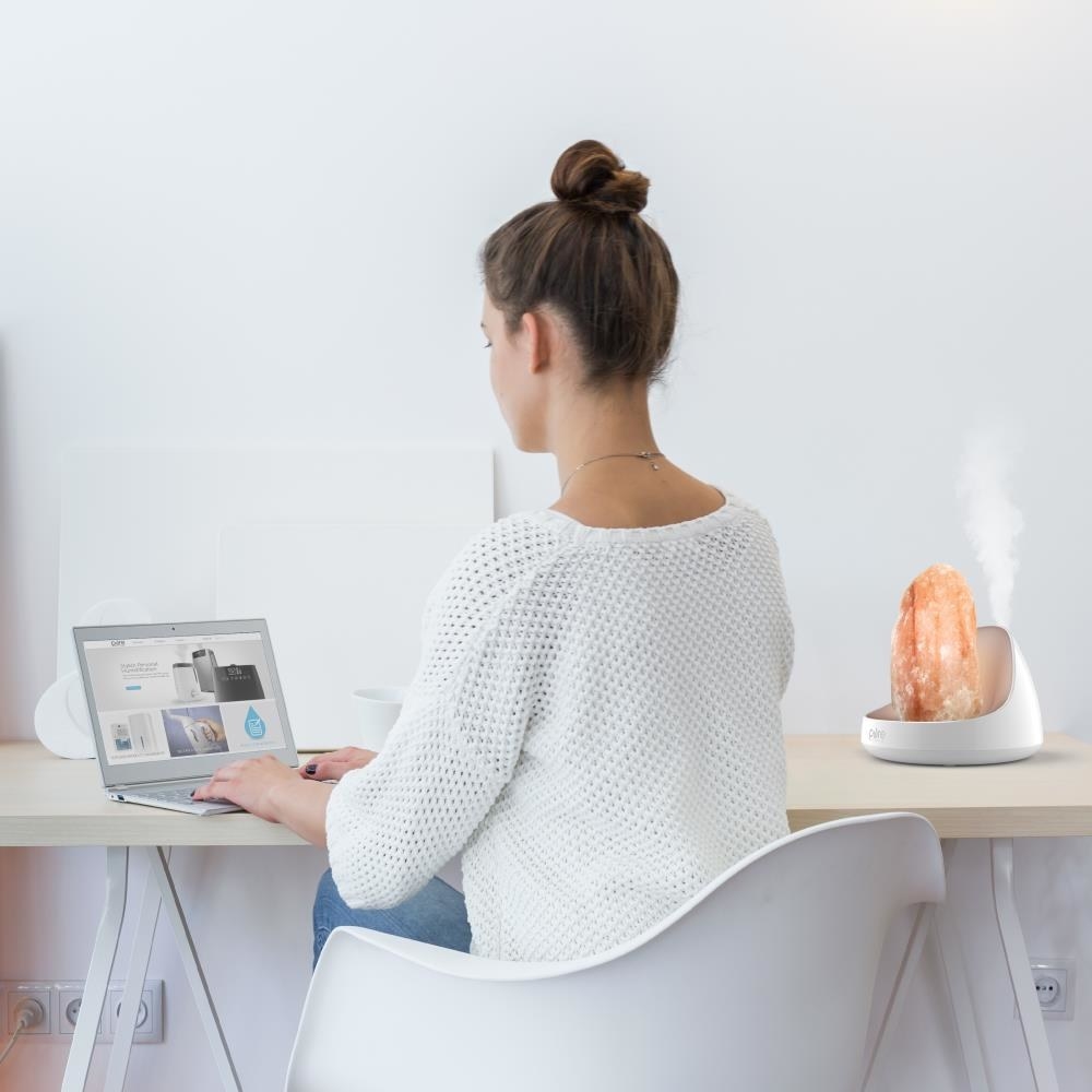 person using the salt lamp and oil diffuser on a desk
