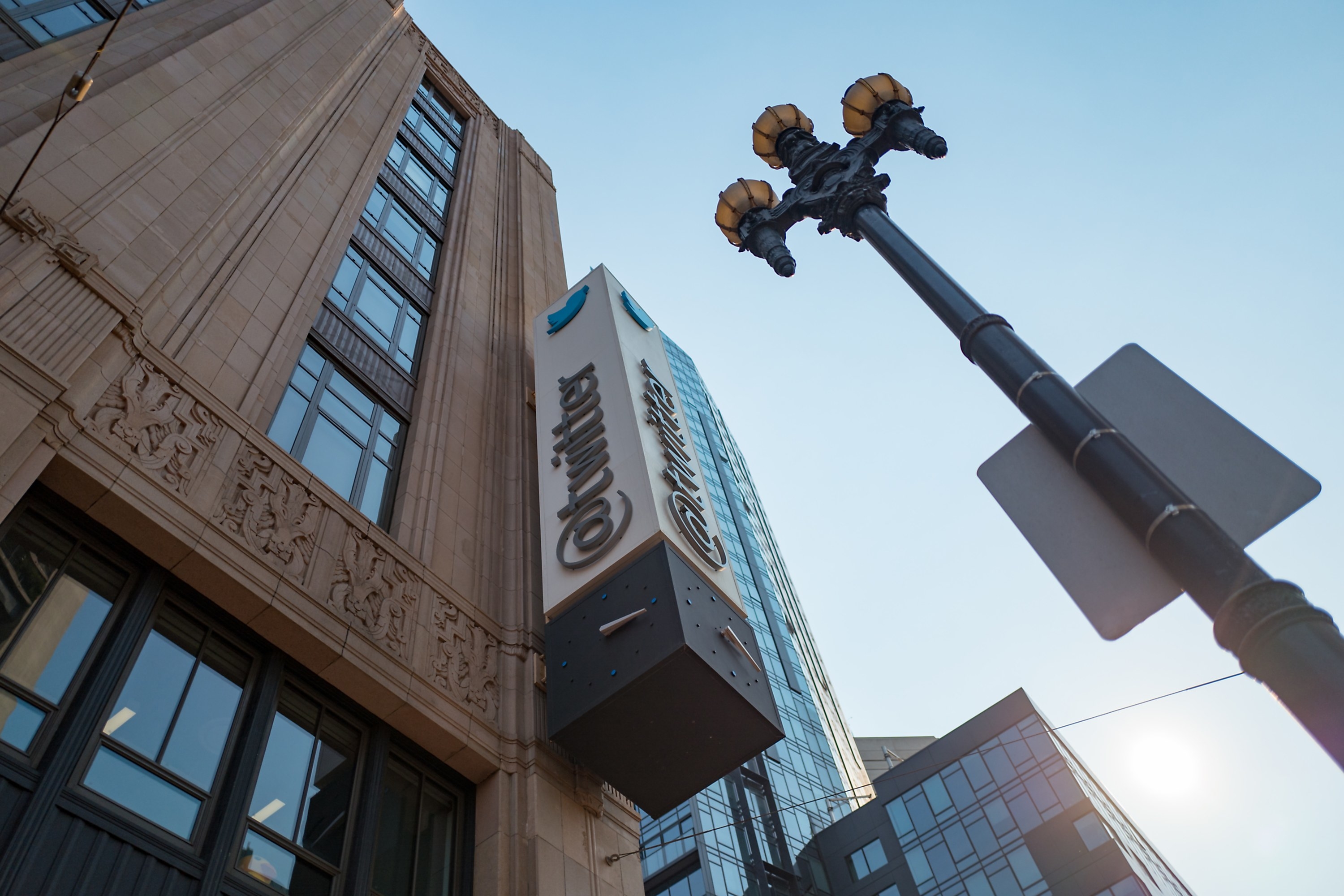 Low-angle view of sign with logo on the facade of the headquarters of social network Twitter in the South of Market (SoMa) neighborhood of San Francisco, California, October 13, 2017