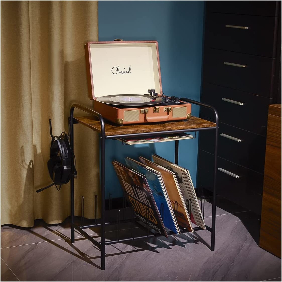 The record player stand with several albums, a player, and headphones on it