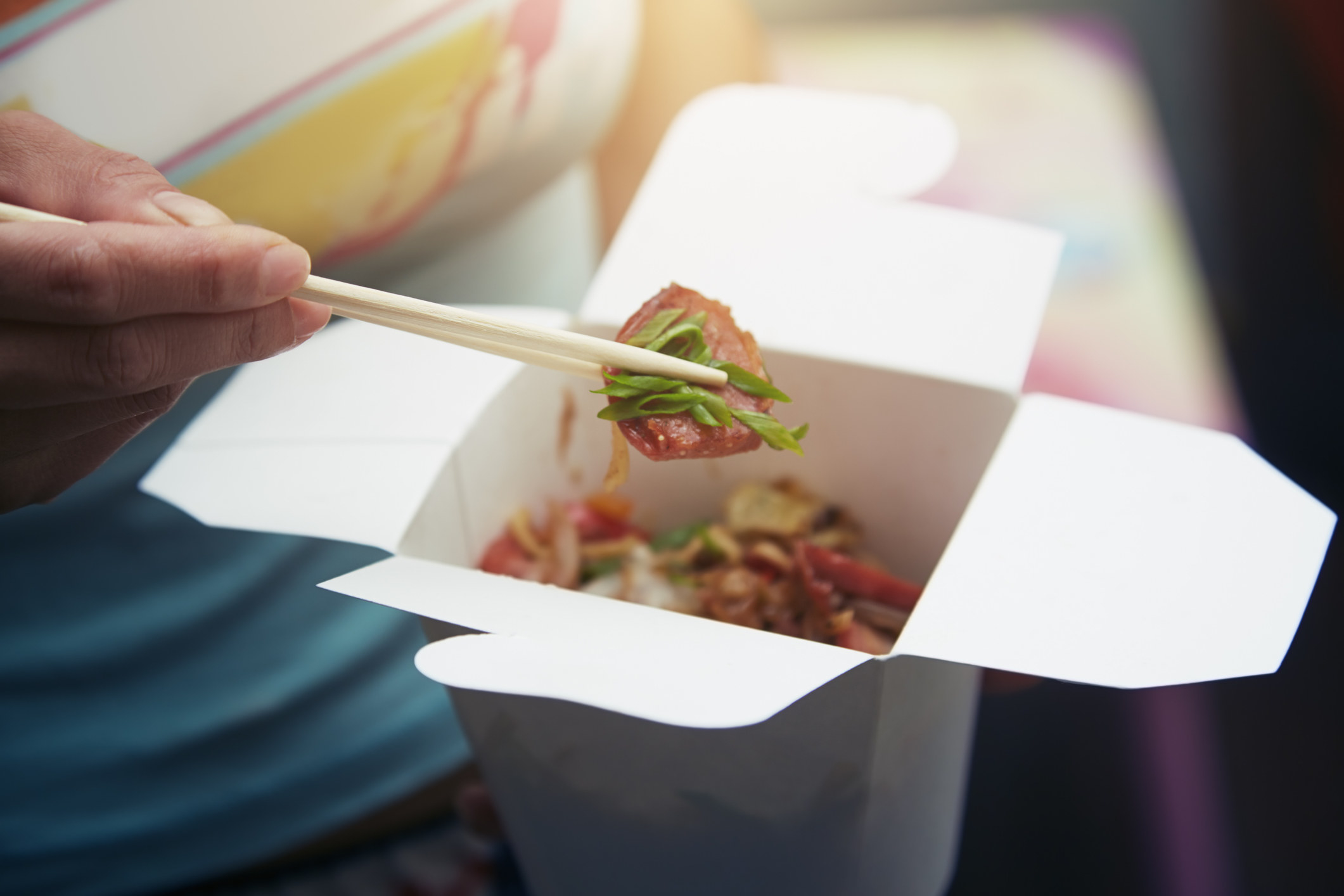 A woman eating Asian fast food from a cardboard box