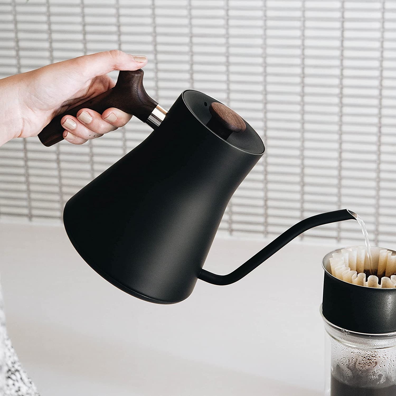 a person using the fellow kettle to make pour over coffee