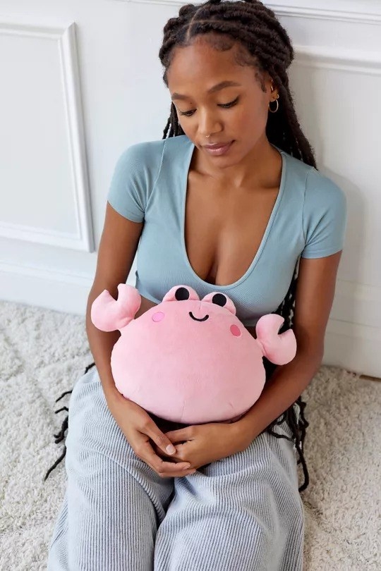 a model holding a plush crab-shaped heating pad