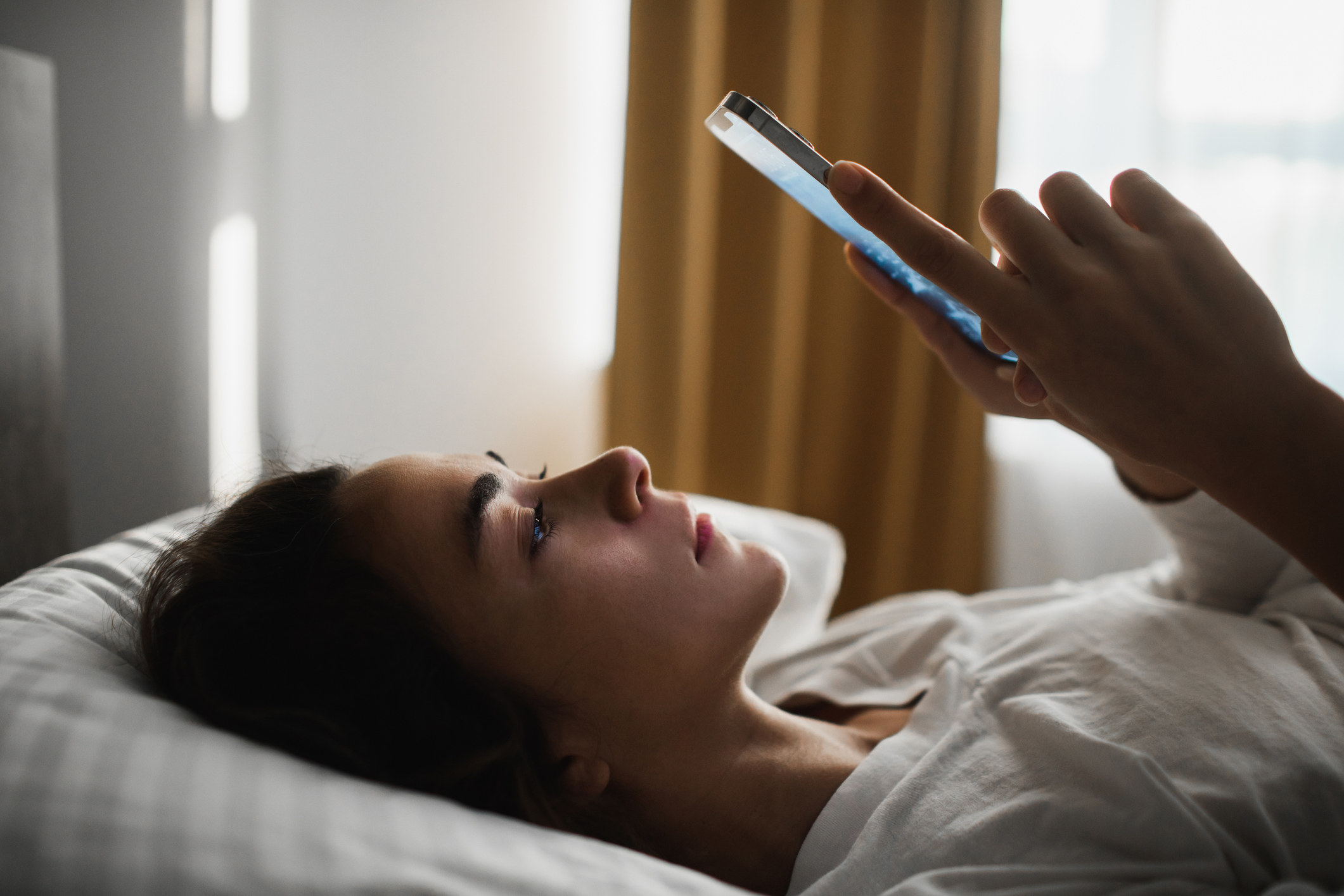 女人躺在床上看着她的手机