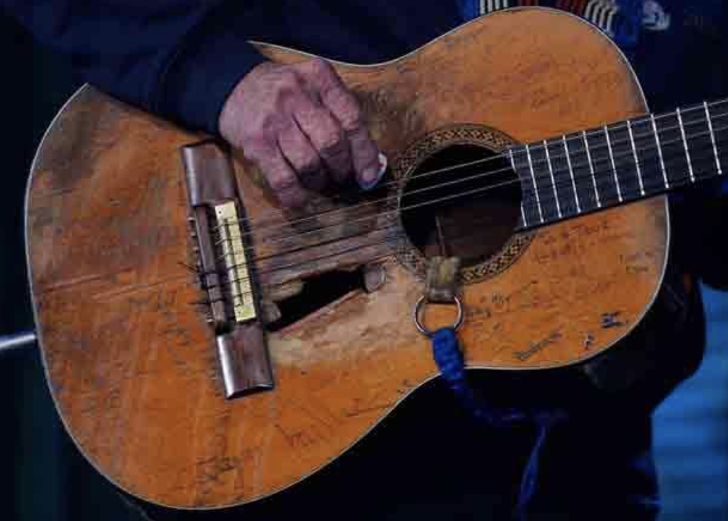 Decrepit-looking wood guitar with extra hole in front