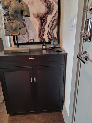 the two-door, one-drawer brownish furniture adjacent to the beforehand doorway of a reviewer's home, closed