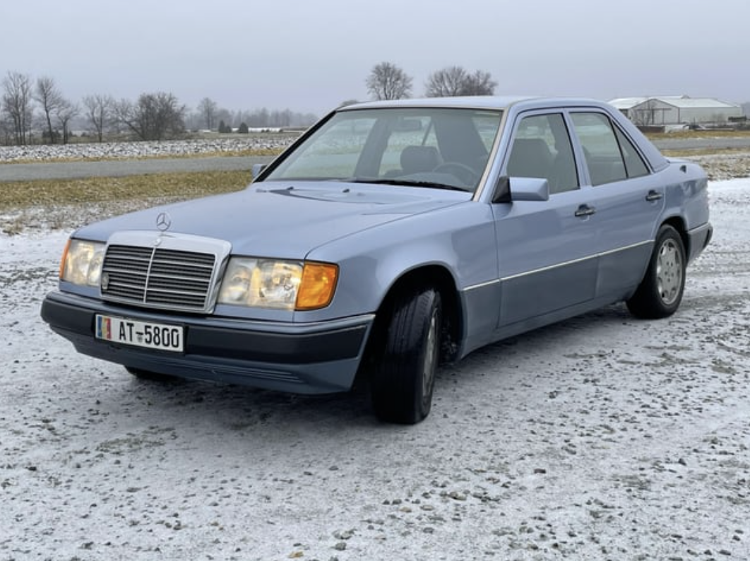 A midsize four-door blue car on gravel