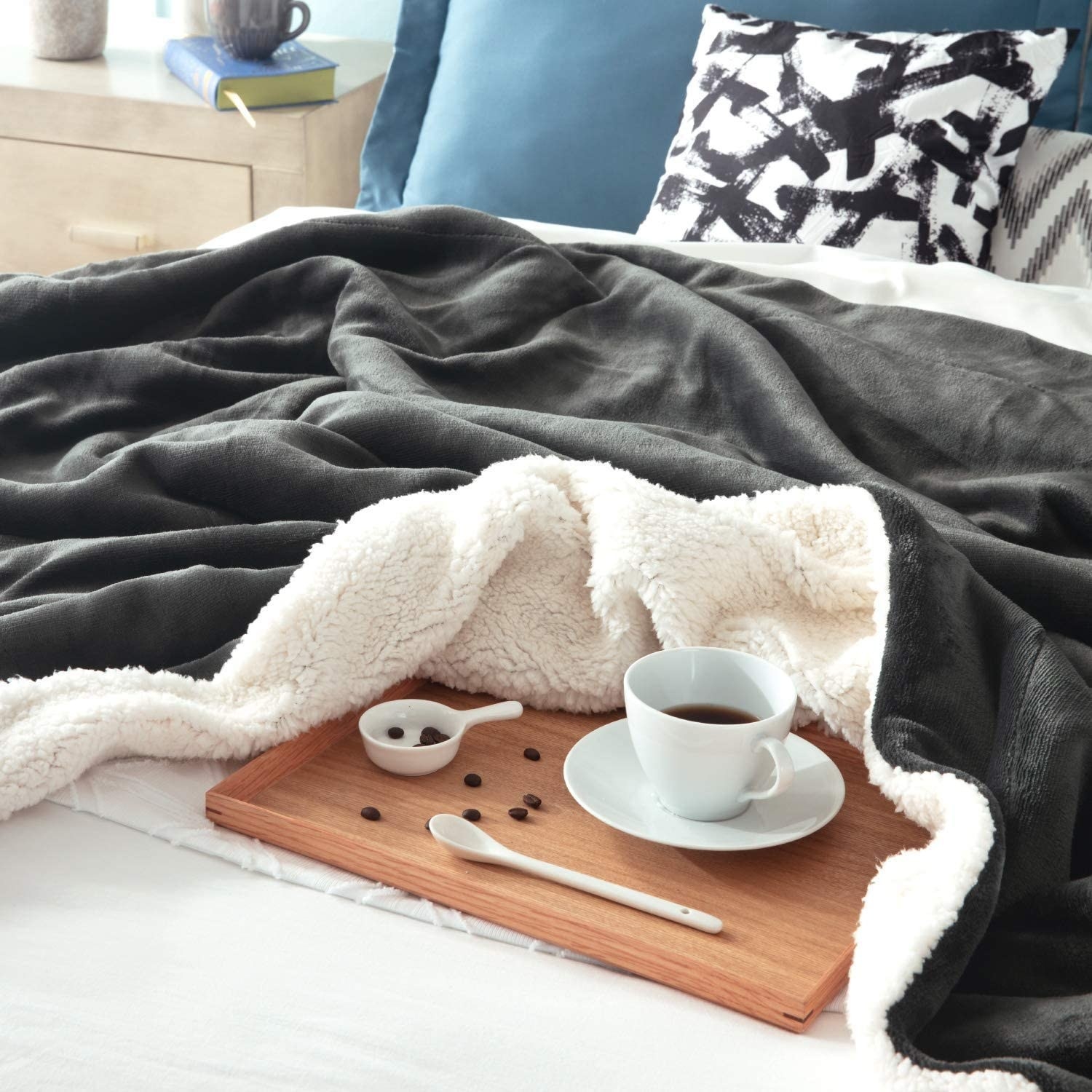 The blanket on a bed surrounding a serving tray with coffee on it