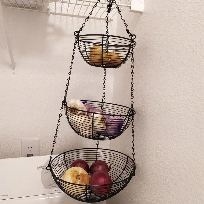 Black three tier fruit basket in corner holding vegetables