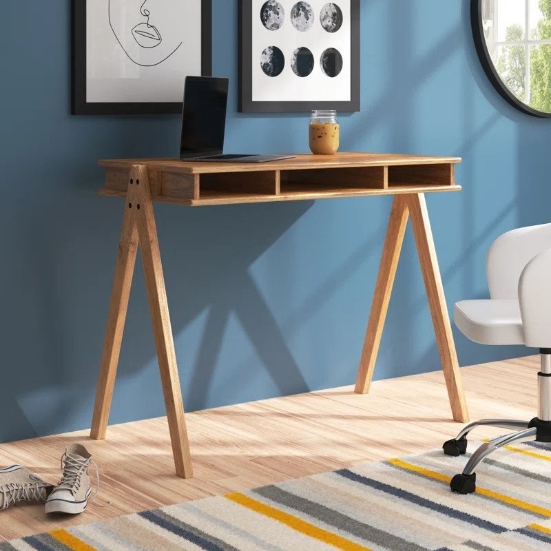 Open cubby wooden desk with laptop and cup of iced coffee on top