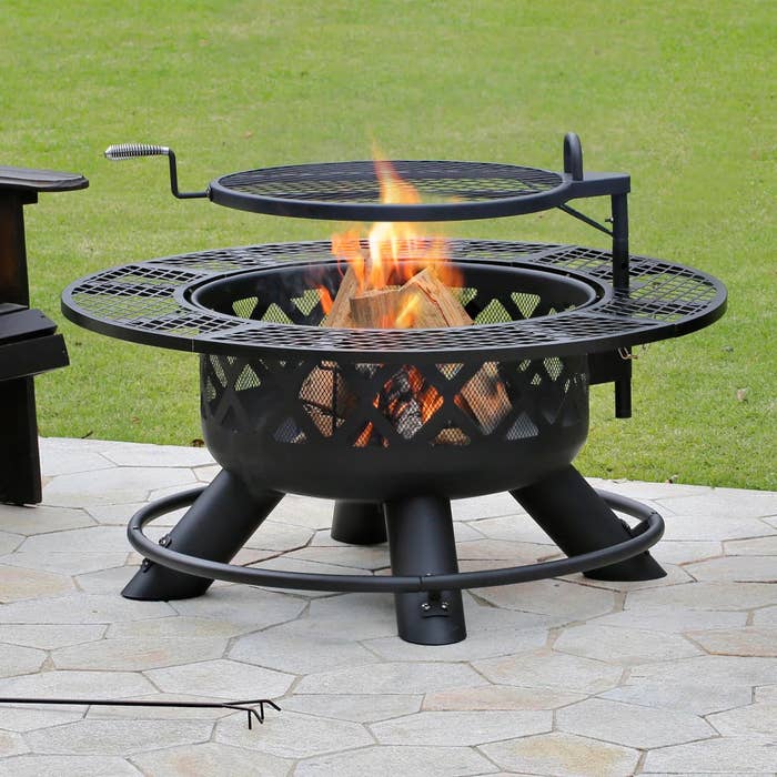 a lit fire pit on a patio in a backyard