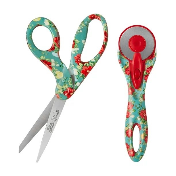 a pair of red floral scissors and rotary cutter on a white background