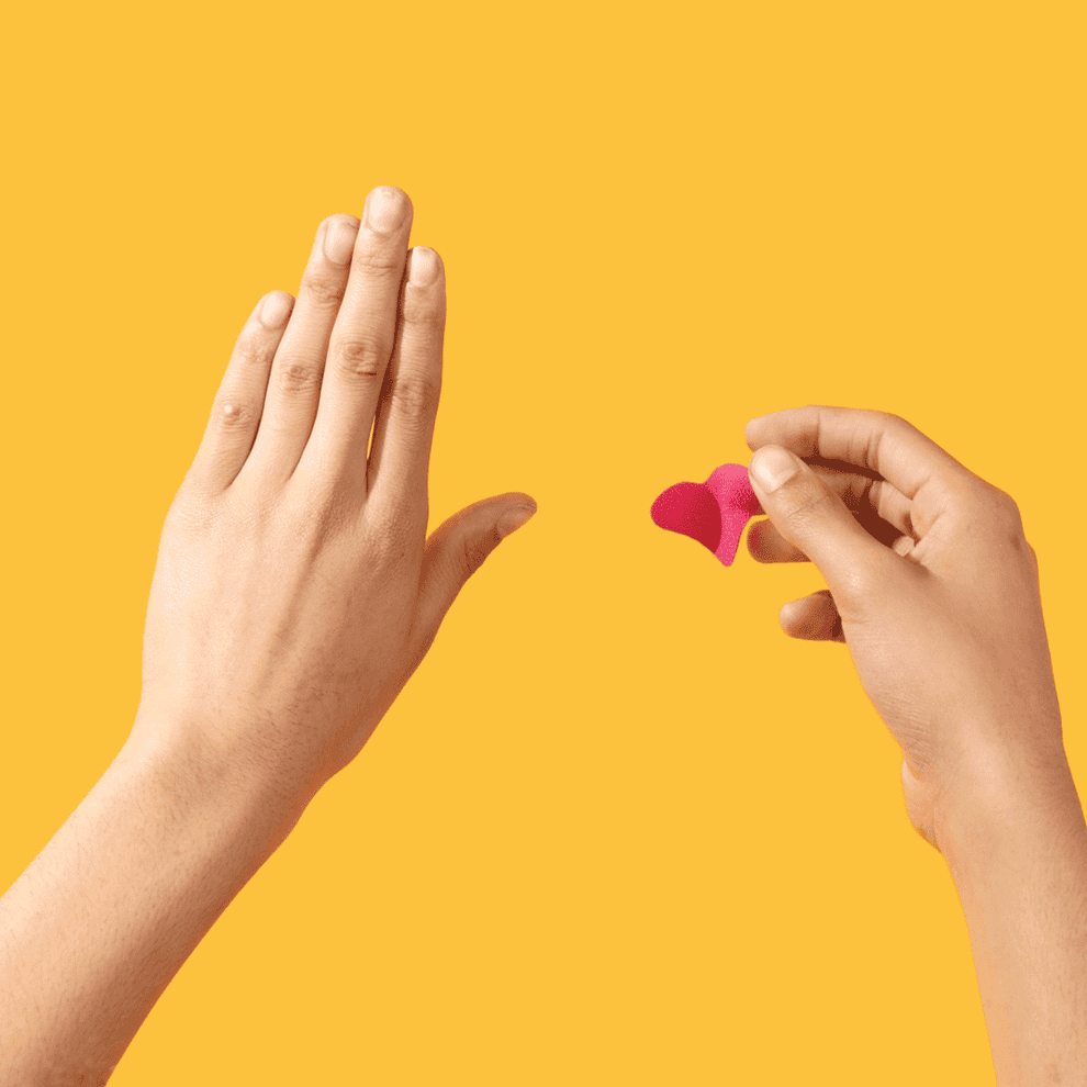 gif of a pink heart-shaped sticker patch being applies to a hand