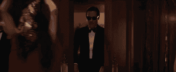 Movie gif: Brad Pitt in a tux grabbing a drink as he walks into a party