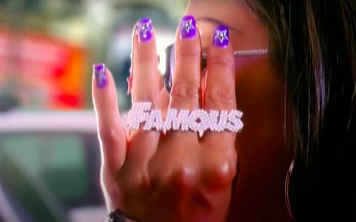 a woman adjusting her glasses and wearing a ring that says &quot;Famous&quot;