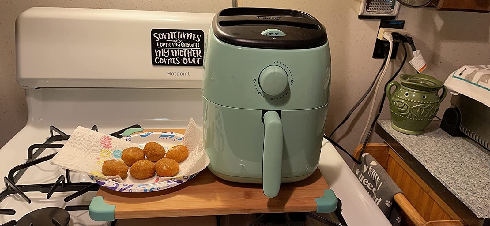 Reviewer image of blue air fryer next to a plate of air fried food